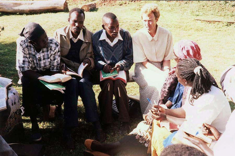 White woman and black Kenyans discuss the Bible in a circle