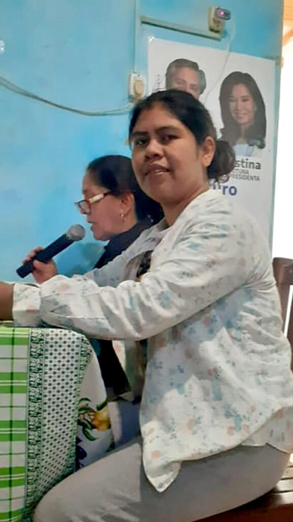 Two women at table, one speaking into microphone