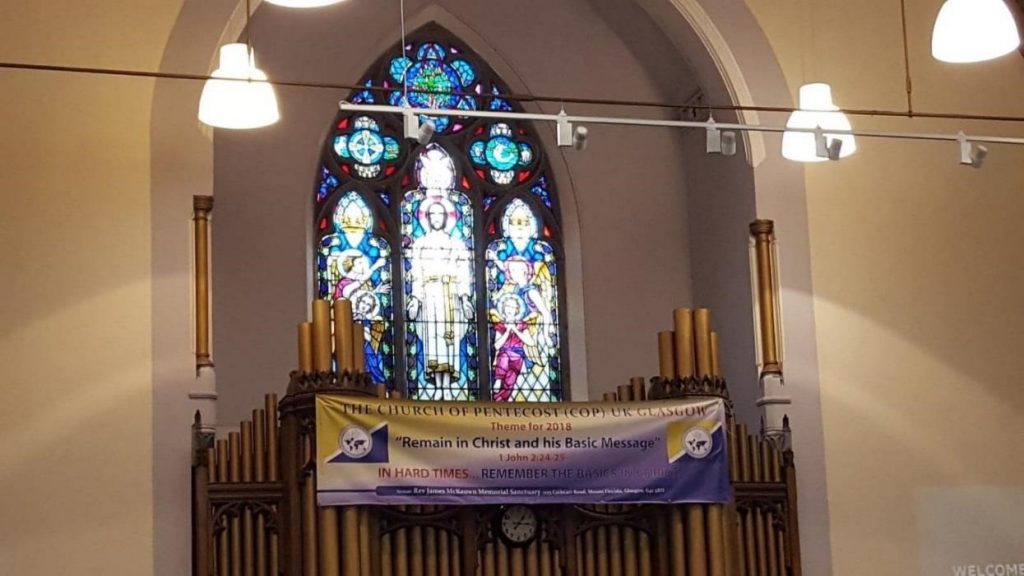 traditional church organ beneath stained glass window, hung with banner of a Pentecostal church