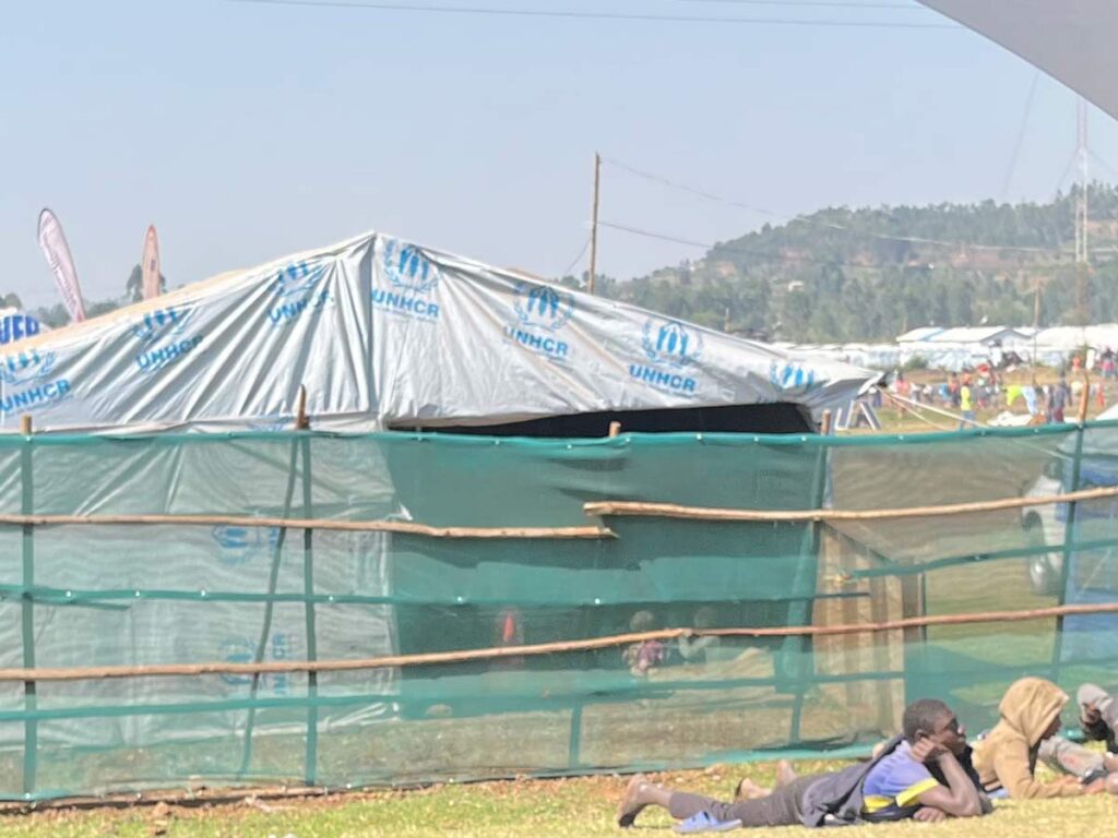glimpse through the perimeter fence of refugee camp