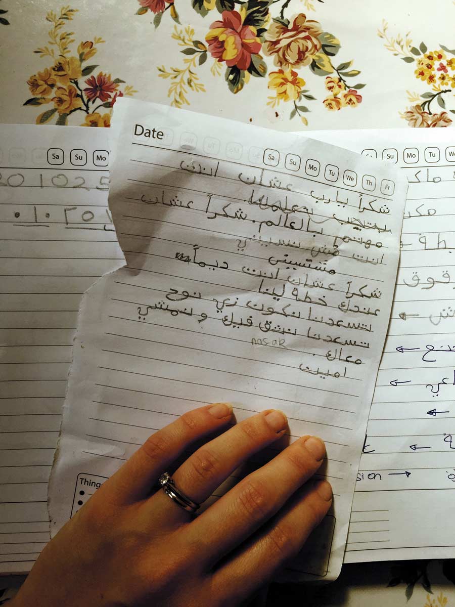 Woman's hand holds handwritten notes in Arabic
