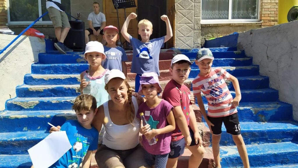 Smiling mission partner Alison and children in sunshine
