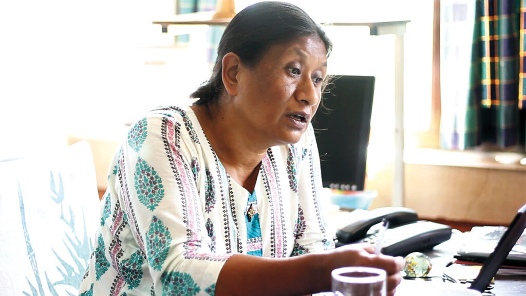 Dhana Lama talking, seated at desk