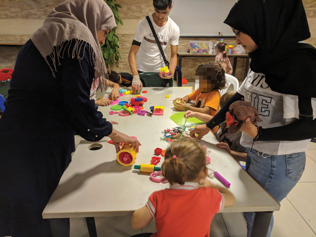 Syrian parents helping children play wth play dough