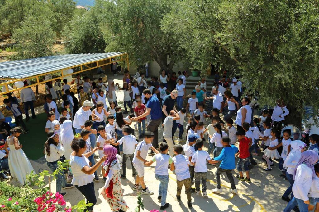 children and adults join in dancing outdoors in a shaded courtyard