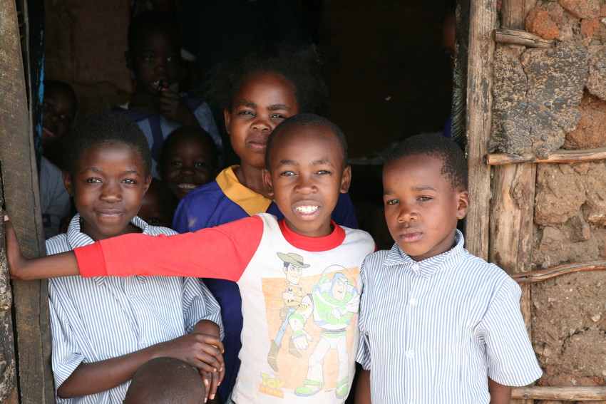four young Kenyan boys confidently pose in a doorway in a very poor neighbourhood of Nairobi