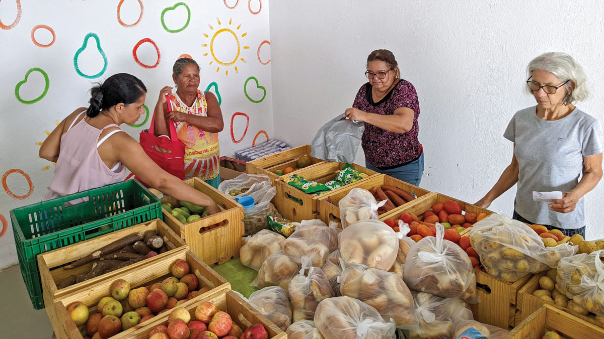 women choose from crates of fresh fruit, vegetables and bread in a bright and airy room
