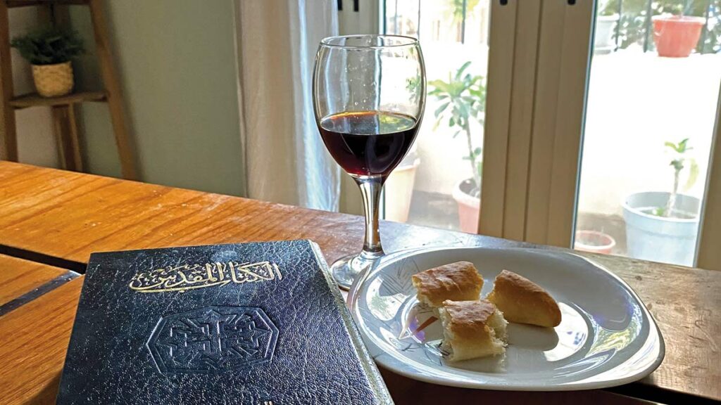 an Arabic Bible, glass of wine and broken bread