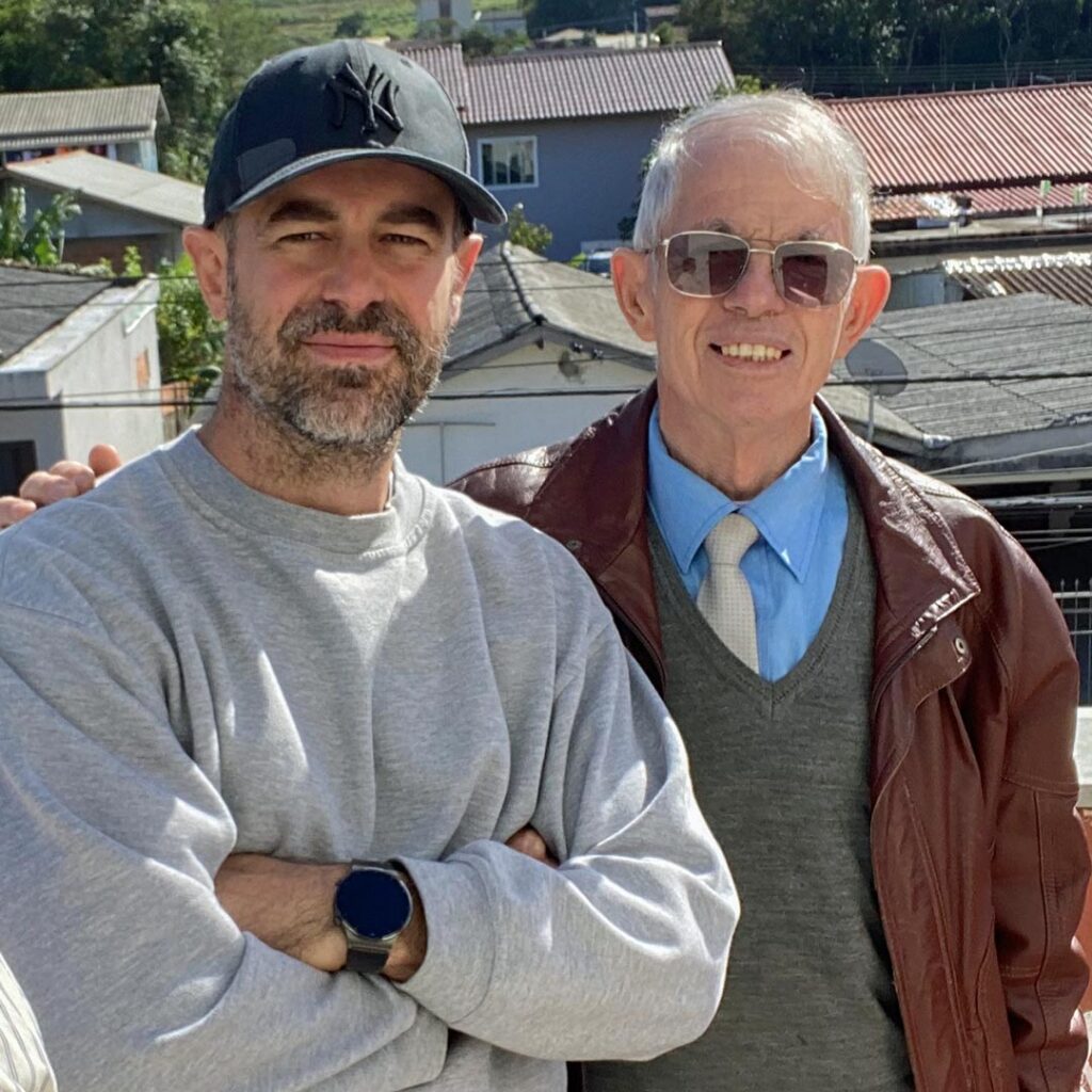 Andy, with light beard and baseball cap, Pastor Antonio, older, with sunglasses, shirt, tie, sweater and brown leather jacket