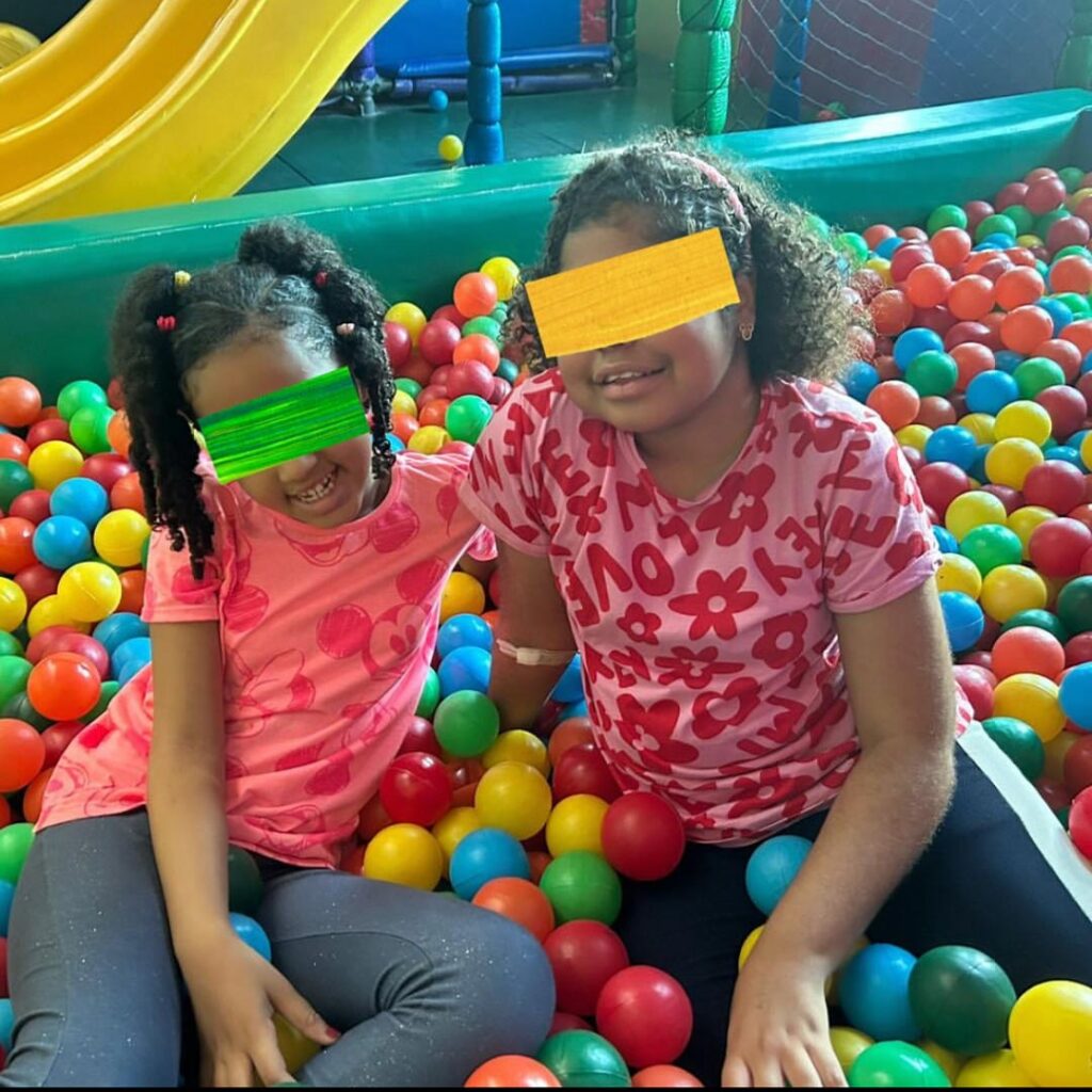 two girls (identities disguised) happily play in ball pit