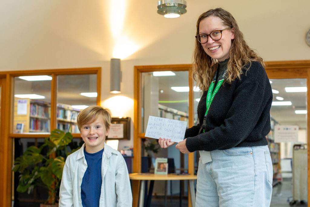 smiling young boy handing donation to equally smiley staff member