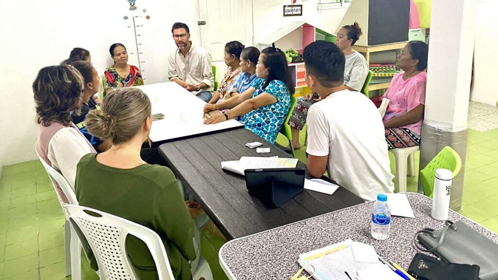 group of Thai people sat round a table with Jon and Elise