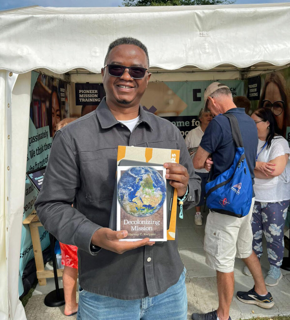 smiling Harvey Kwiyani shows his new book