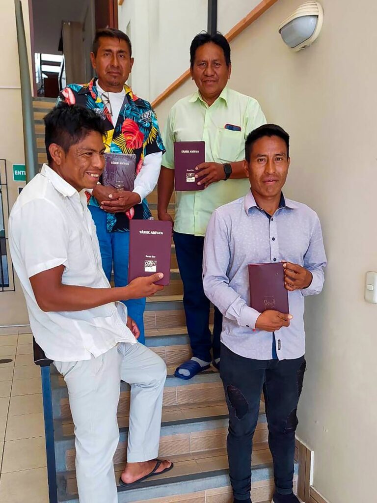 four smiling smartly dressed Enxet men holding Bibles