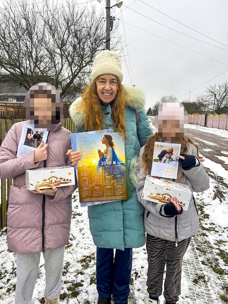 a smiling Alison with two girls, sharing Christmas and New Year gifts