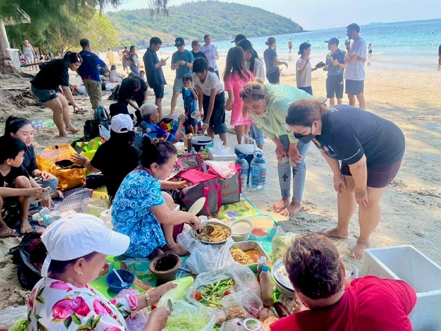 large group gathers round picnic spread on tropical beach