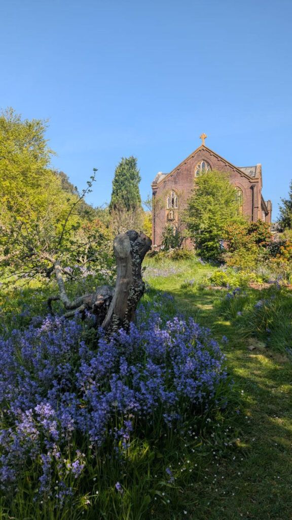 abbey building under a blue sky surrounded by lush greenery