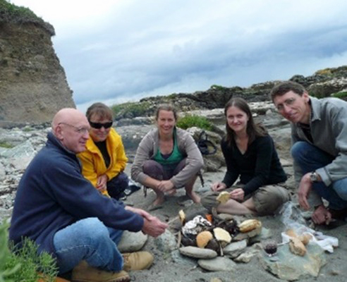 group of five sitting on stony beach