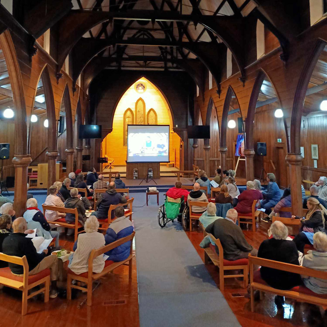 group of people in a church building watch a large screen