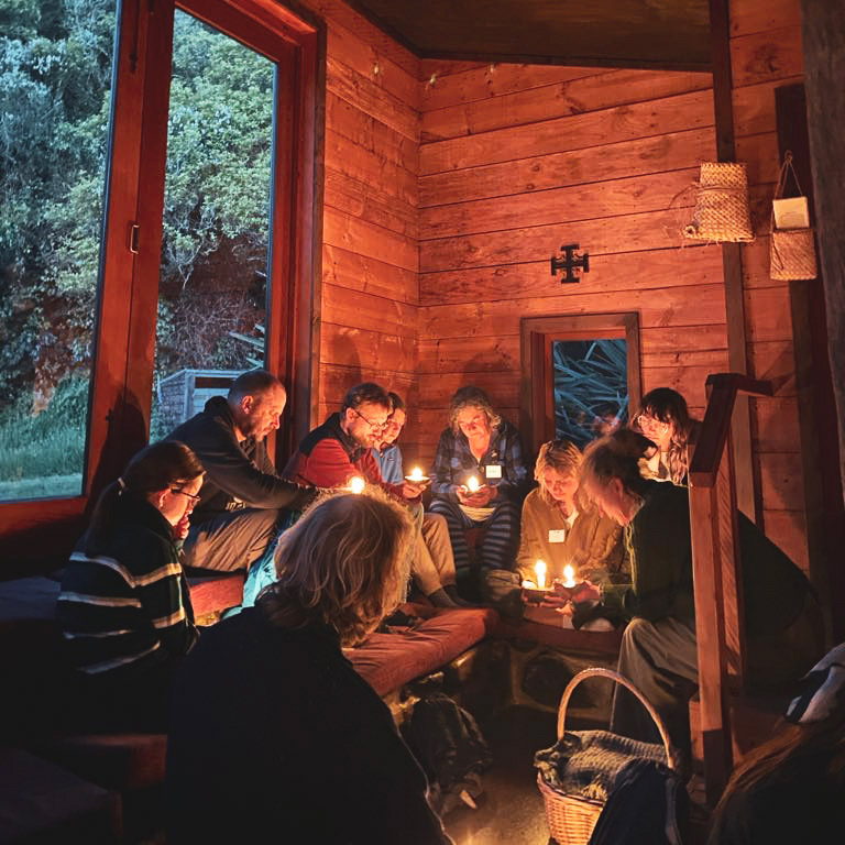 small group holding candles gathered in circle in a cabin