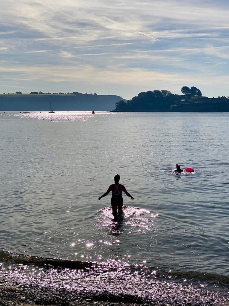 silhouetted woman wades out into sea