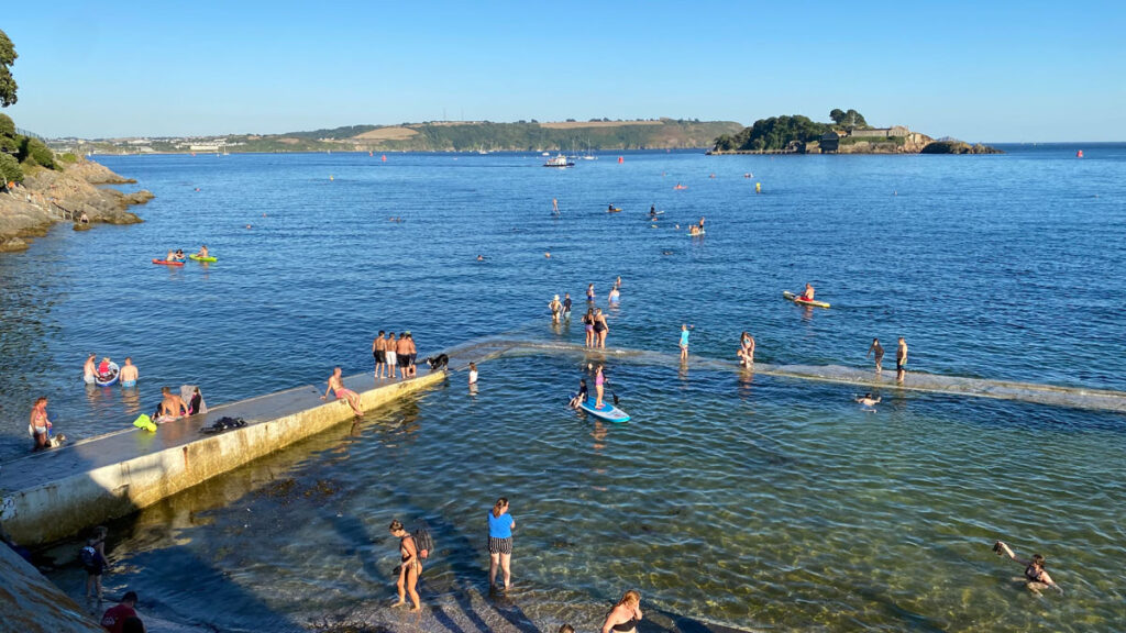 beachside infinity pool full of bathers on sunny day