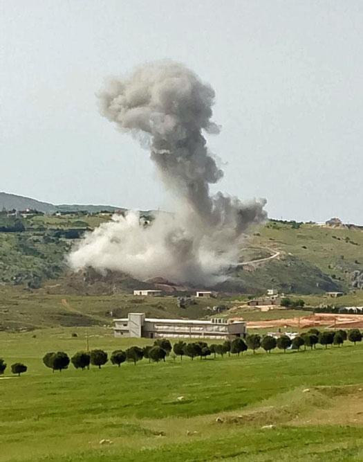 dust cloud rises on hillside as a bomb explodes