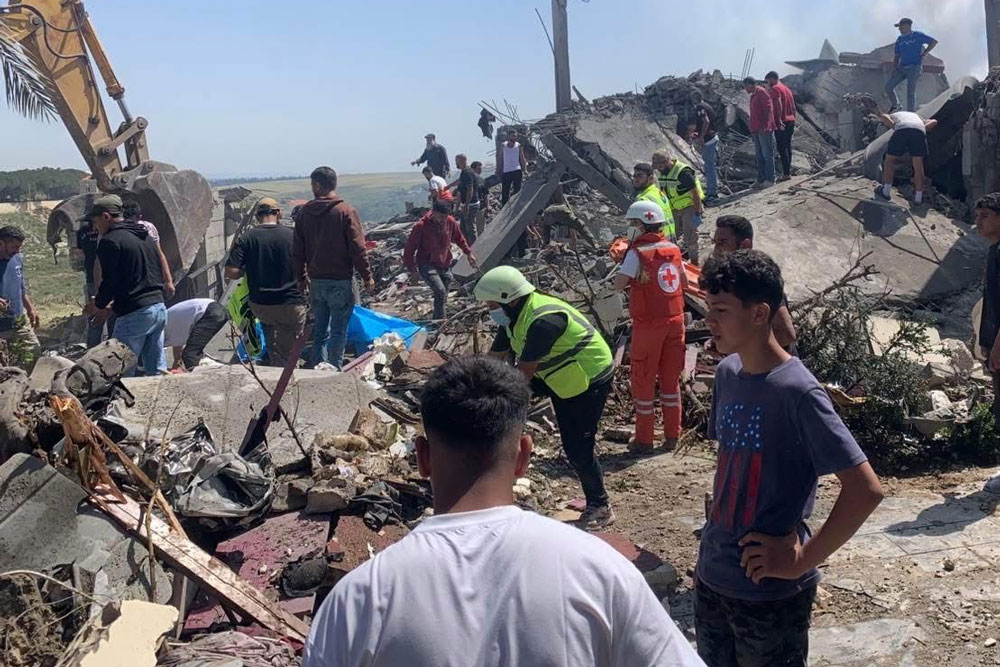 emergency services and civilians attempt to sort through piles of rubble