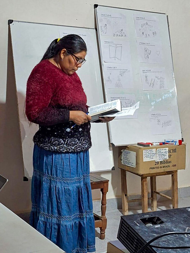 South American indigenous woman reading from a Bible with whiteboard