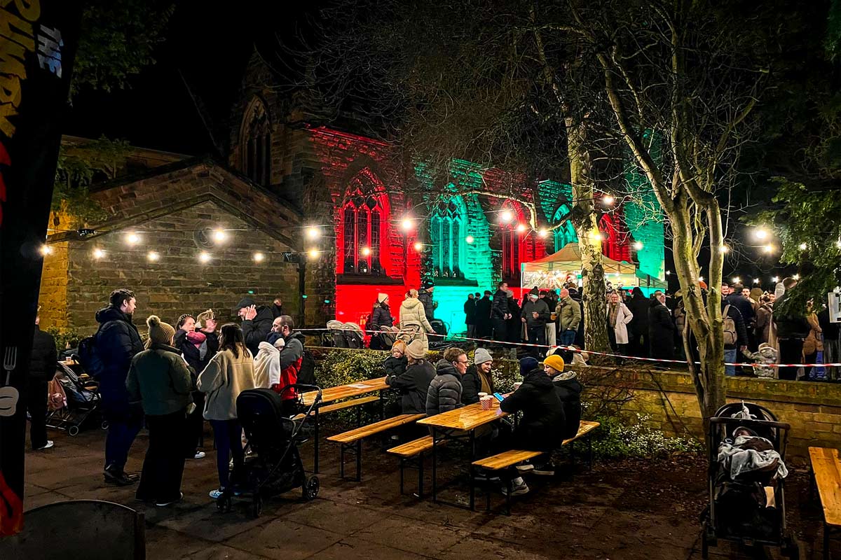 church exterior lit up in red and green, with people milling outside